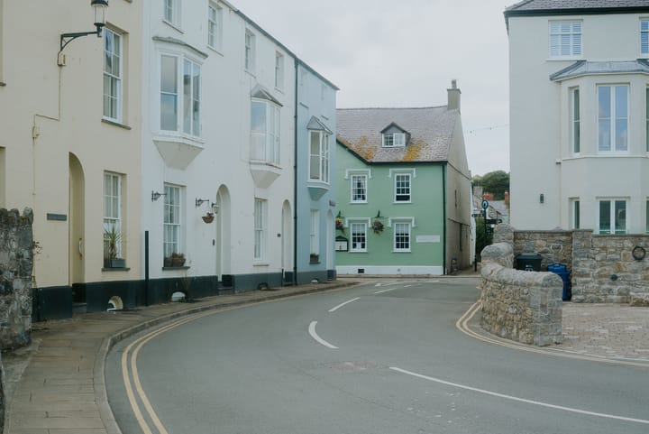 A colourful street in Beaumaris with homes painted green, blue and white.