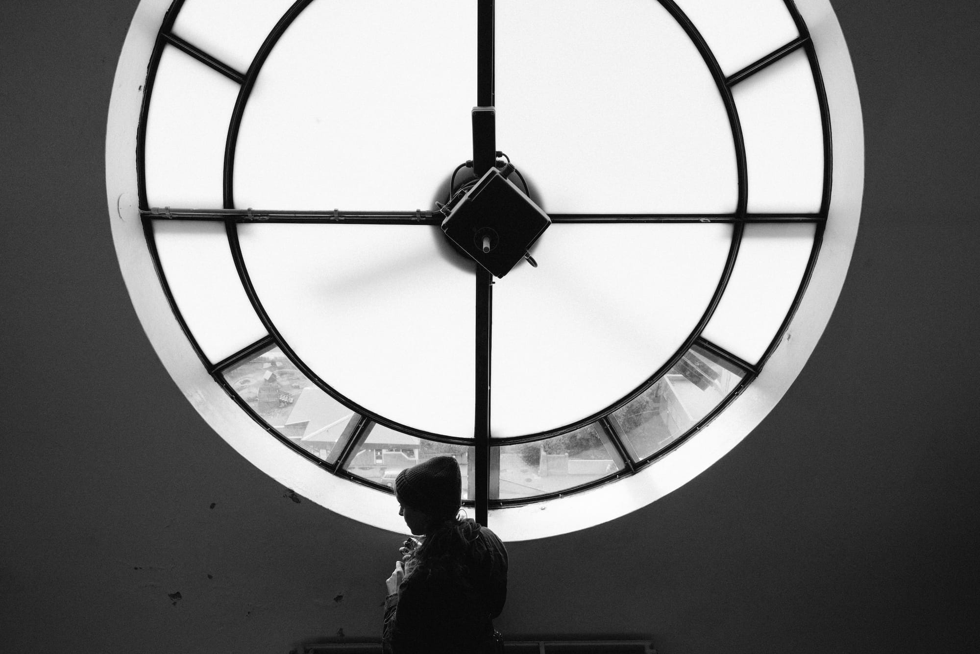 A female preseting person walks past the interior of the clock face in the Hallgrímskirkja church.