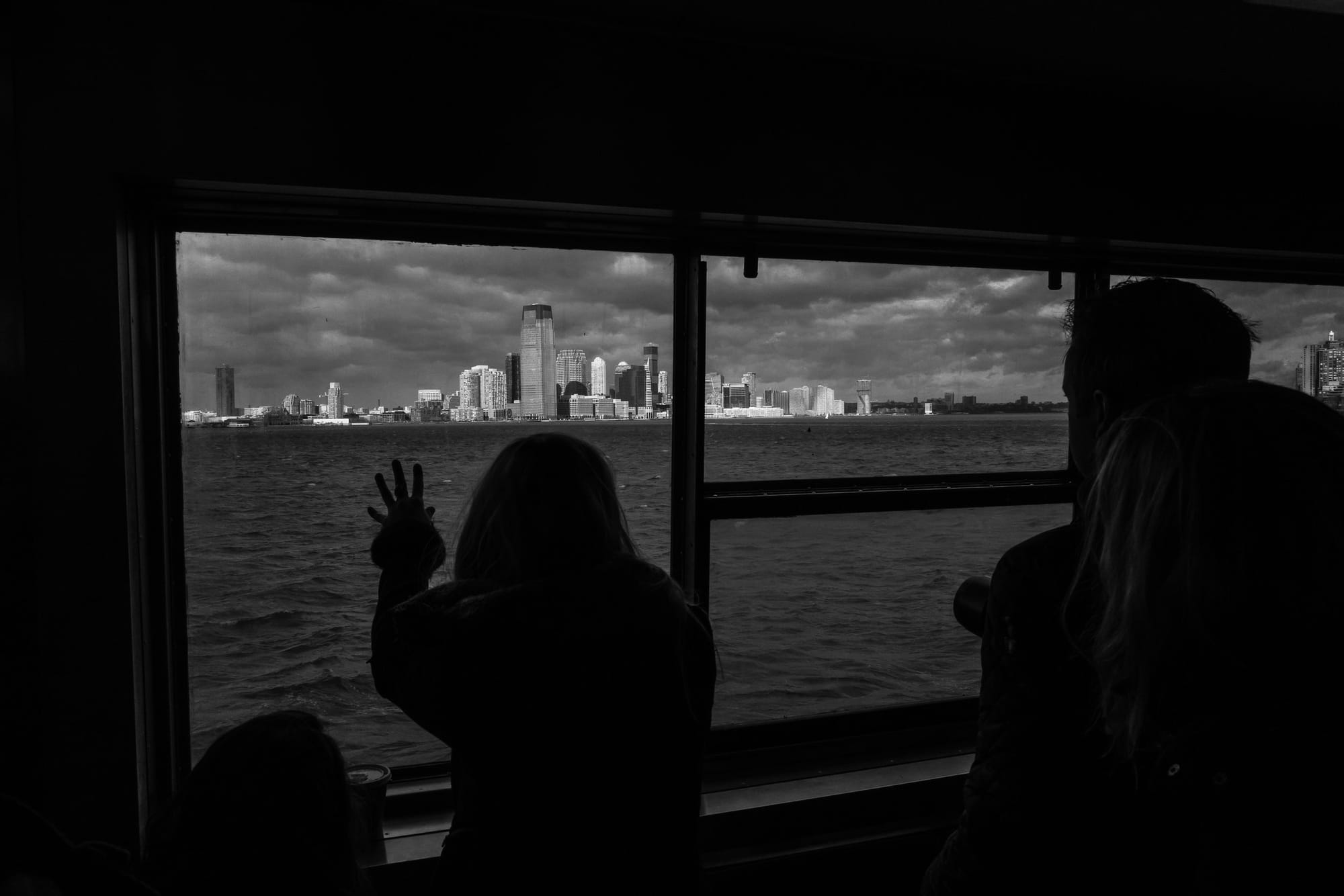 A woman puts her hand on the window as the Staten Island ferry sails away from Manhattan.