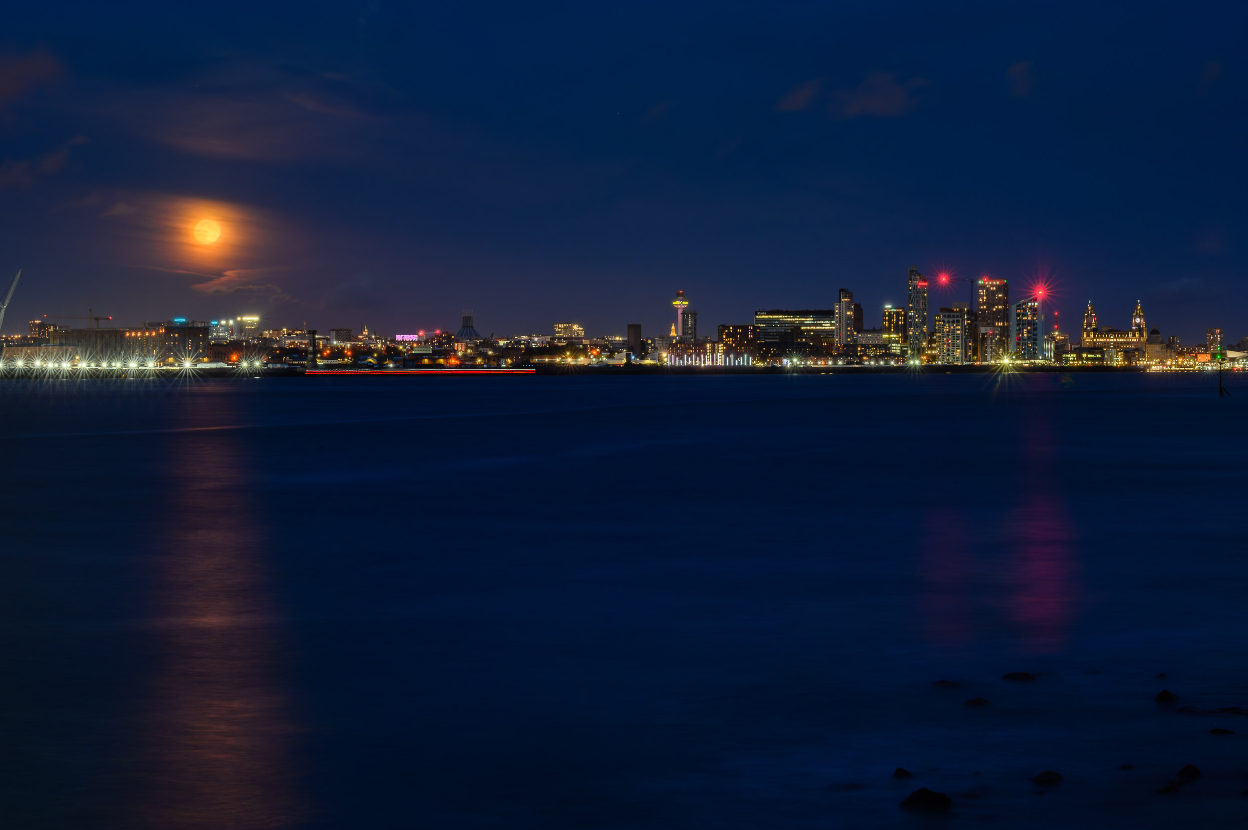 Super blue moon rises through the clouds over the Liverpool waterfront.