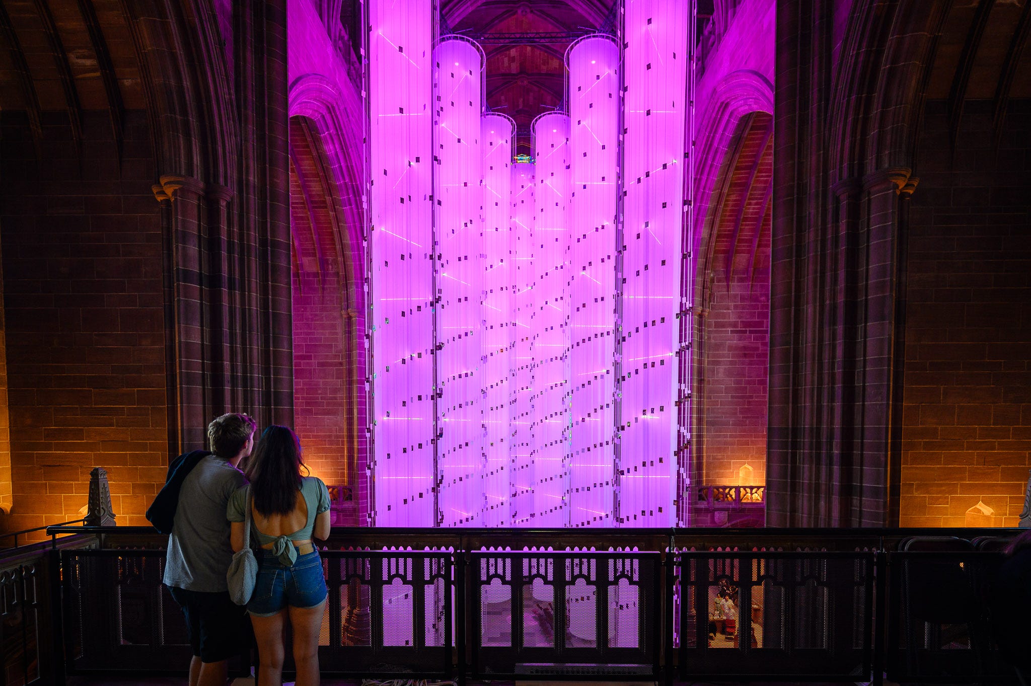A couple look at the pink columns of light from the elevated vantage point.
