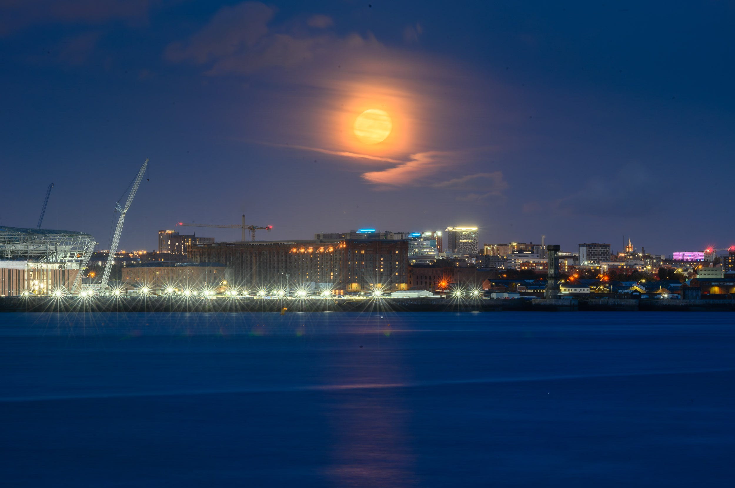 Super blue moon rises through the clouds over the Liverpool waterfront.
