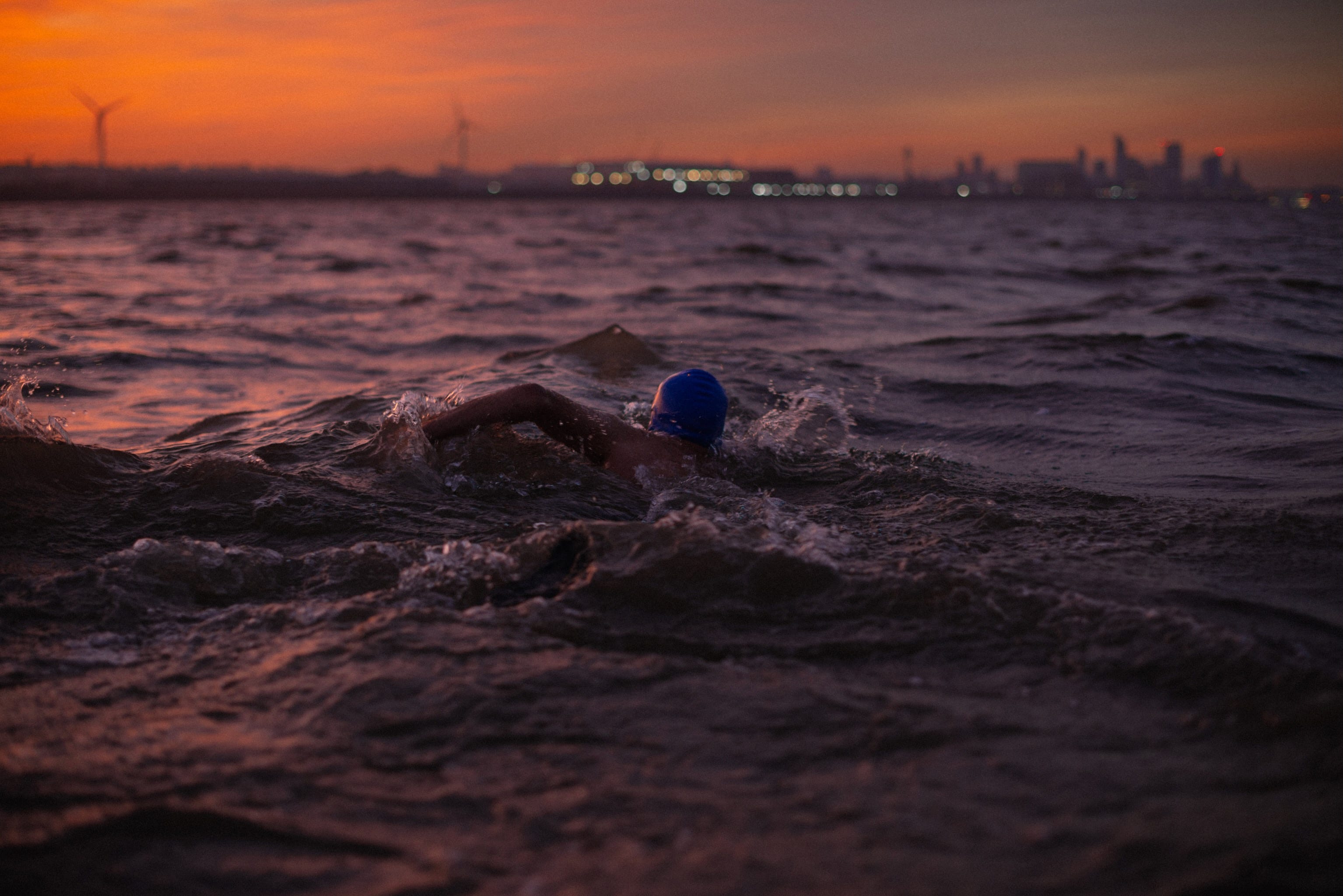 A man swims towards the city of Liverpool as the sun comes up.