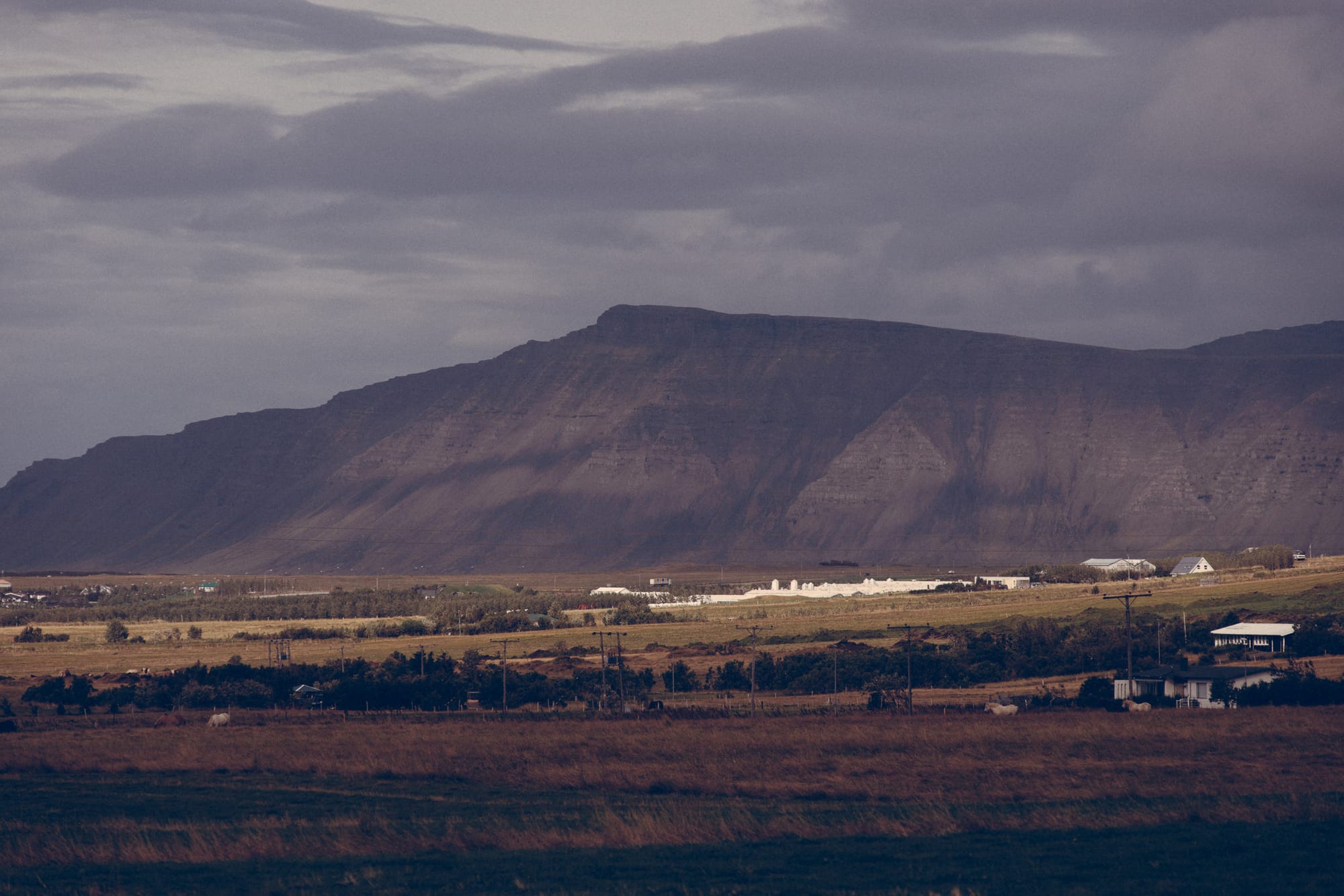 A large mountain dwarfs the houses beneath it.