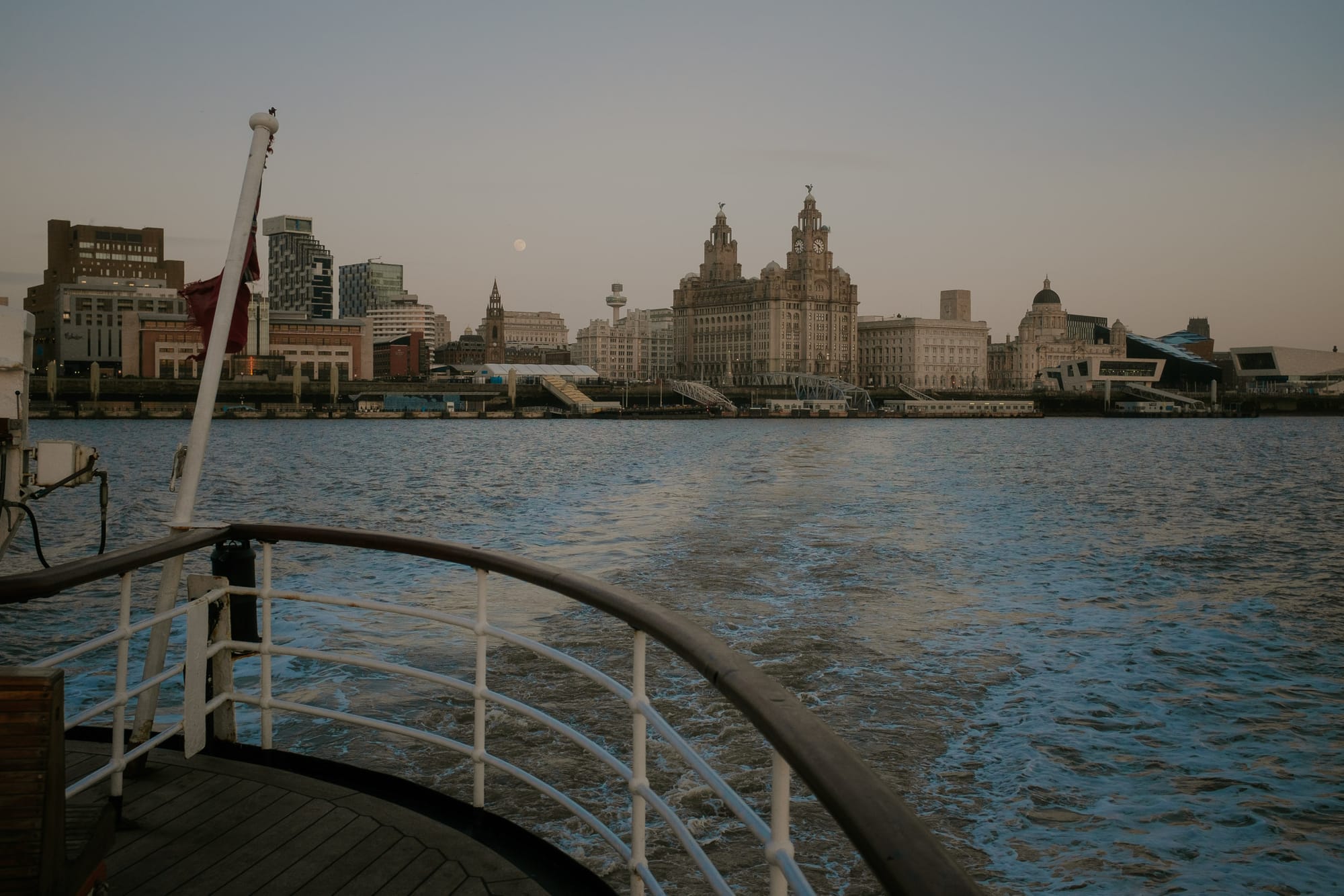 Moonrise behind the city of Liverpool from the decks of a Mersey Ferry. The river is a little choppy and it’s a clear night.