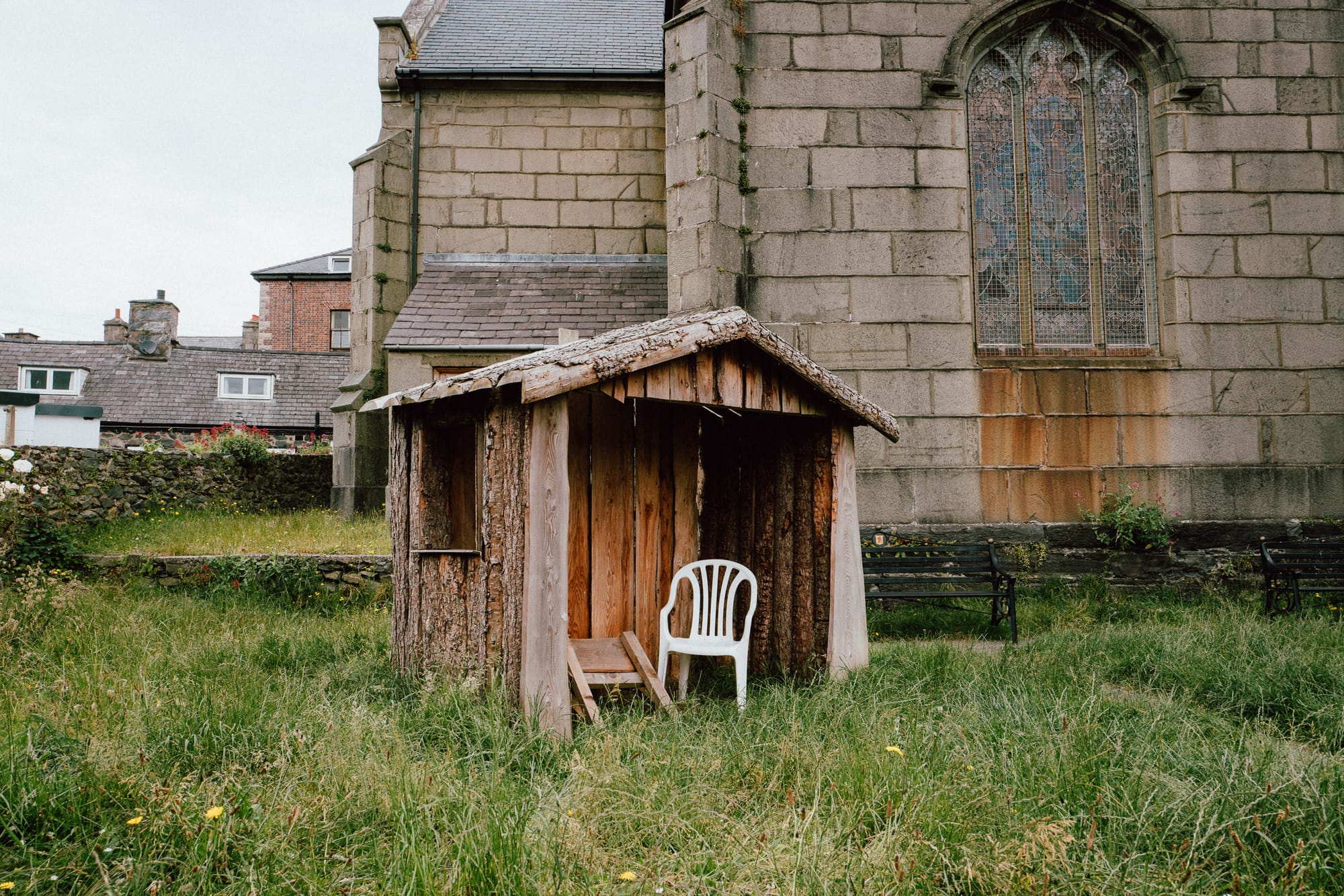 Outside a church there is a little wooden hut with a white plastic seat inside.