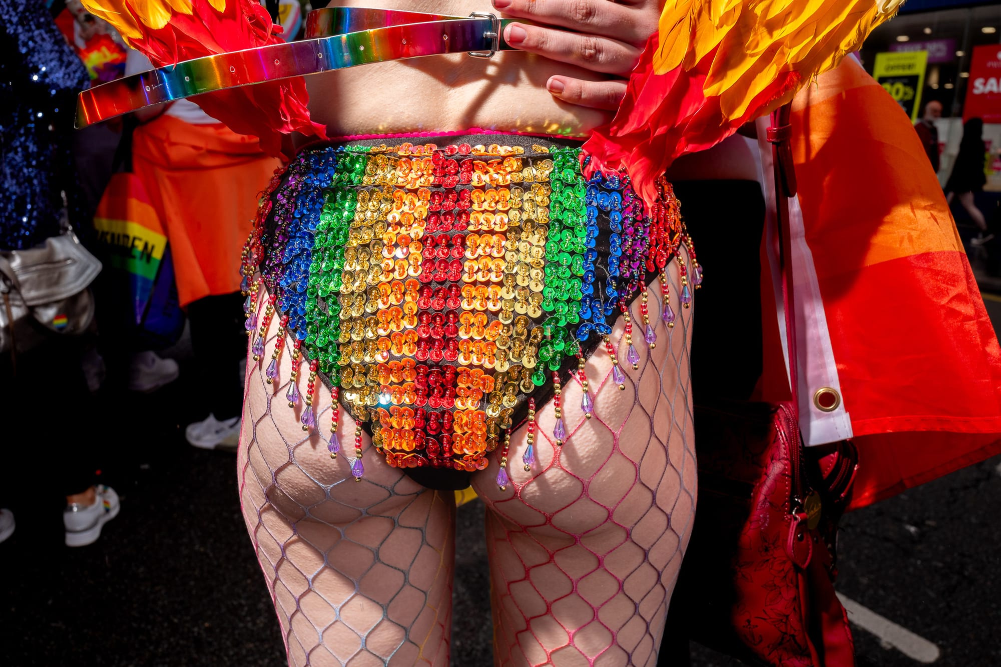 A female presenting bum in rainbow briefs. The person is wearing rainbow fishnets as well.