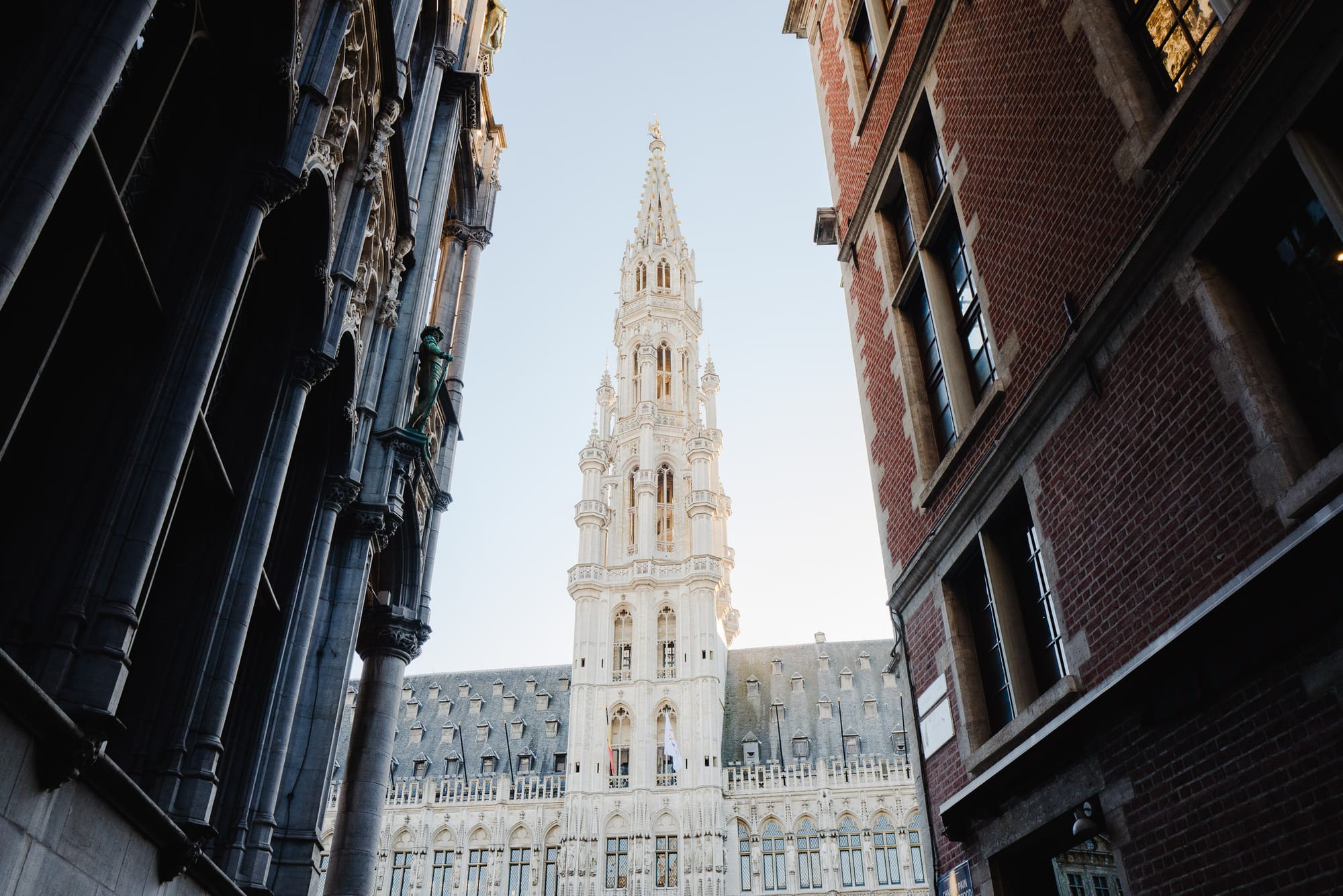 At the end of a street, between two buildings, stands a large ornate spire on top of a grand building.