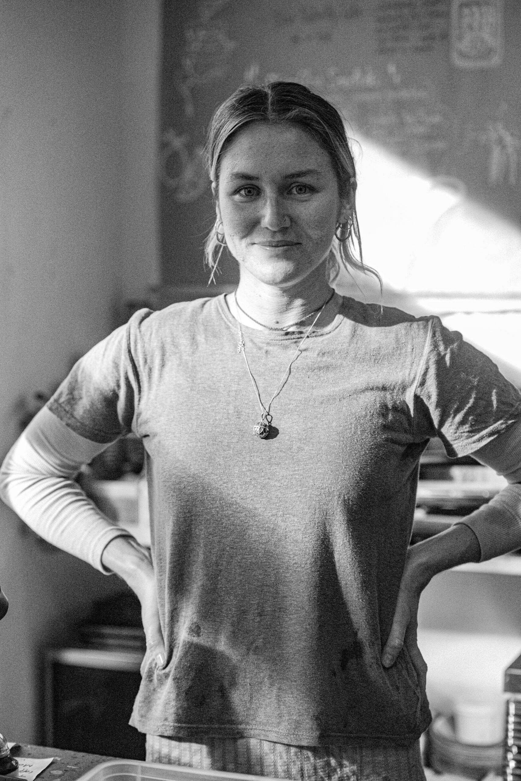 A woman smiles for the camera. SHe's wearing a tshirt over a long sleeve tshirt with a silver necklace.