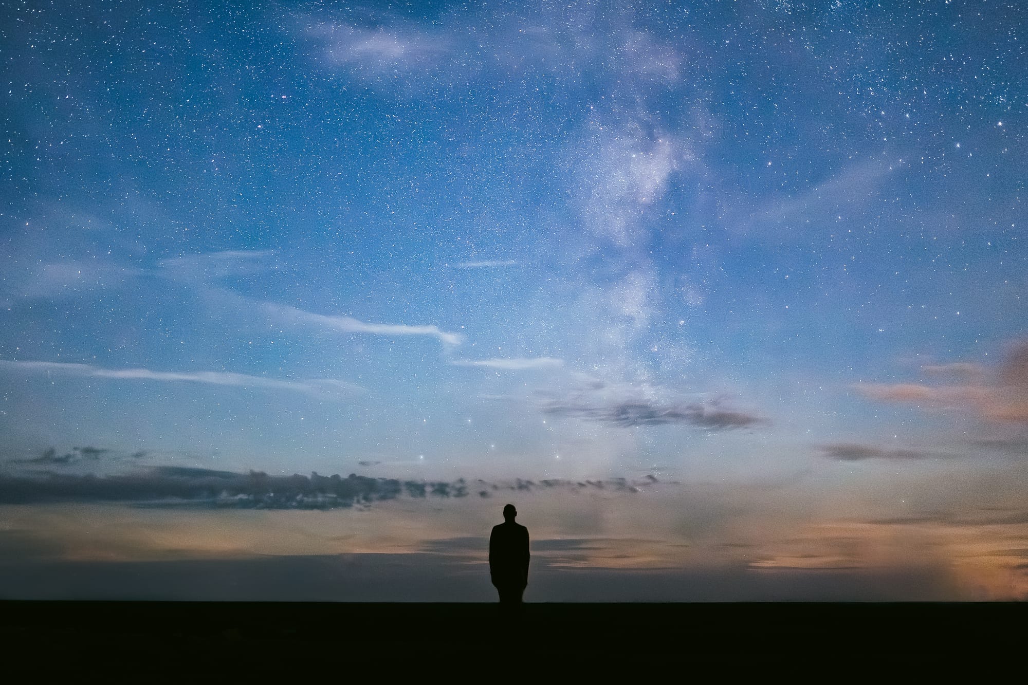 A silhouetted person looks at the nights sky.