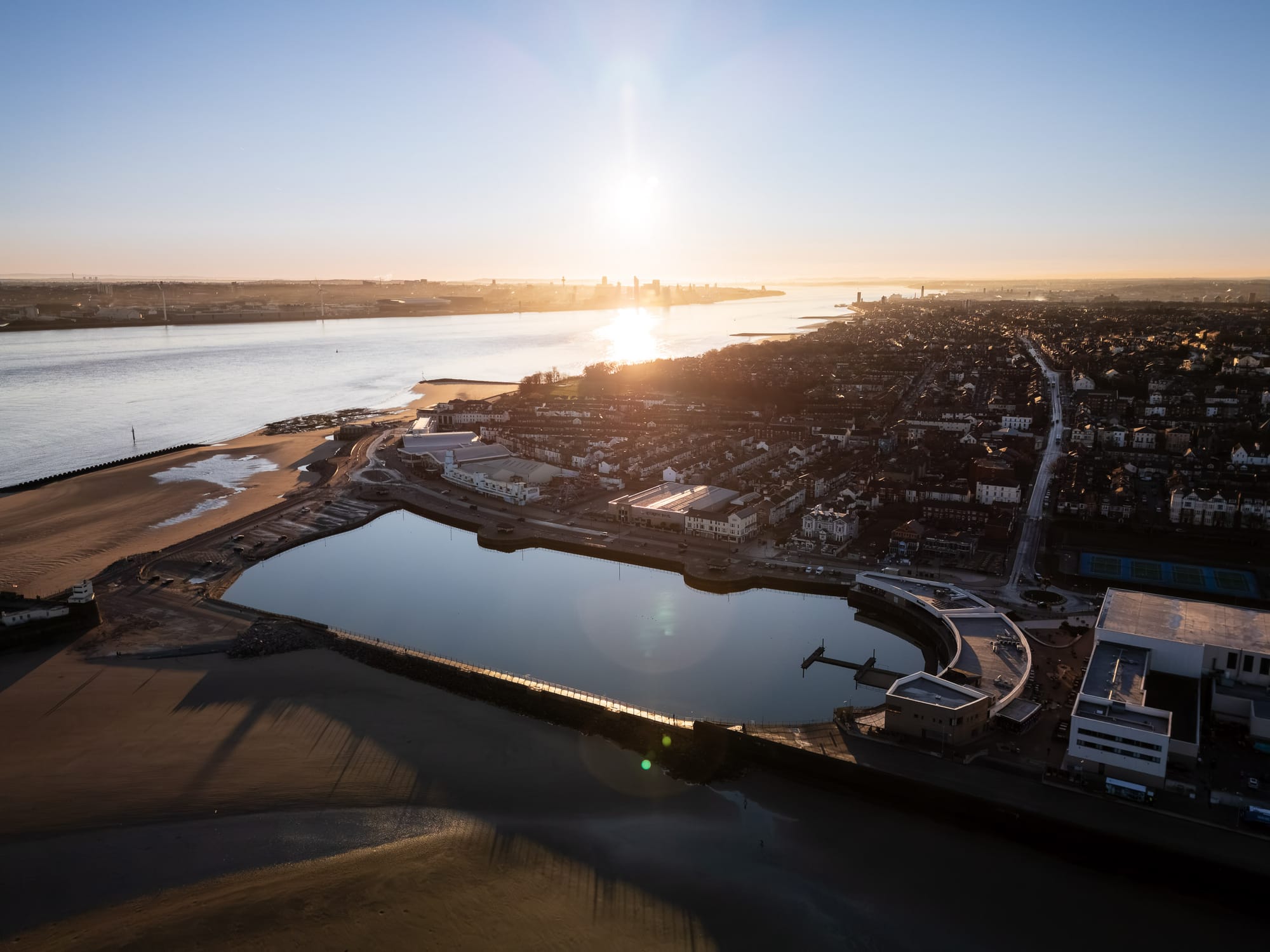 Aerial view of New Brighton Marine Lake and Liverpool skyline at sunrise.