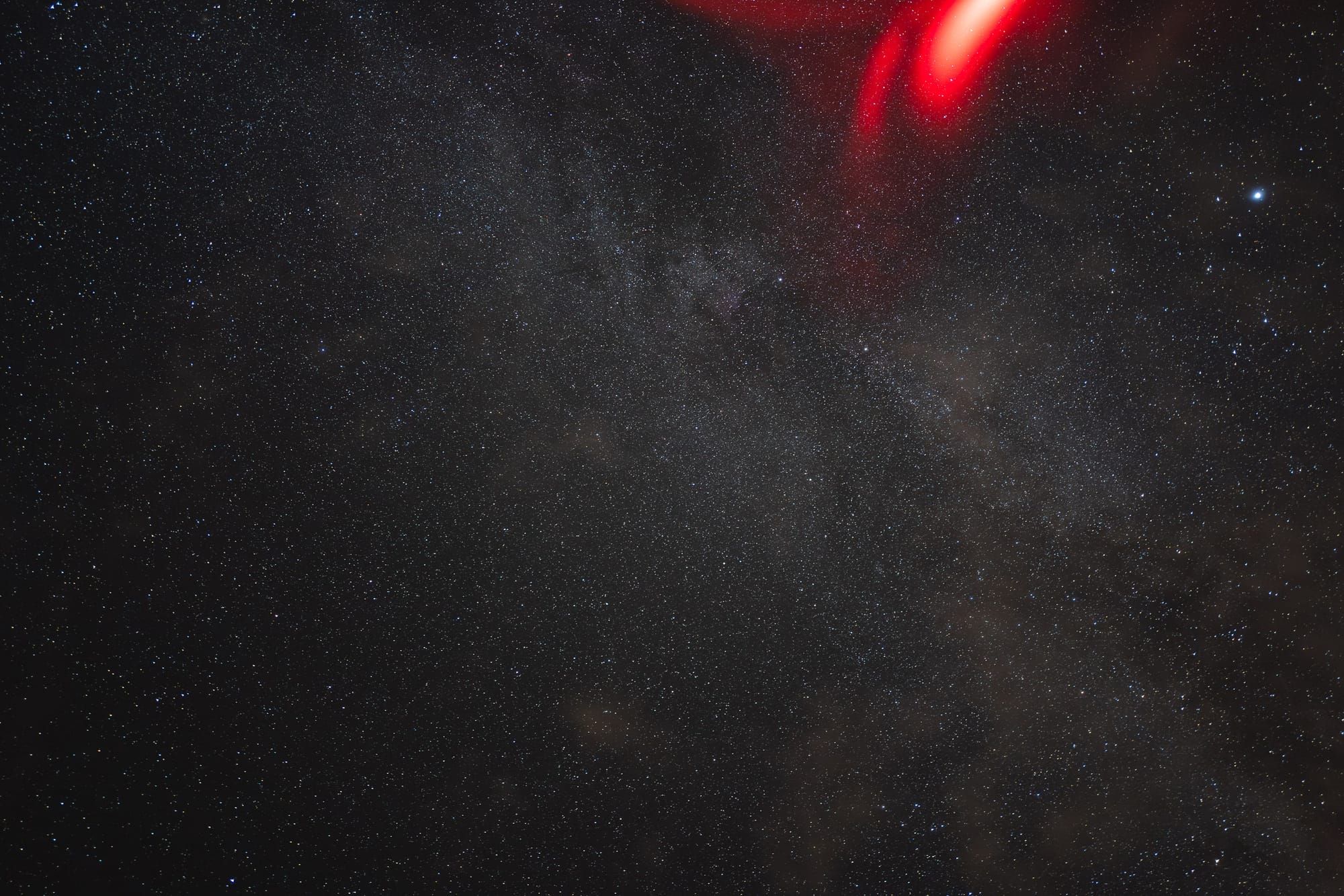 A sky filled with stars. There is a red light in the corner.