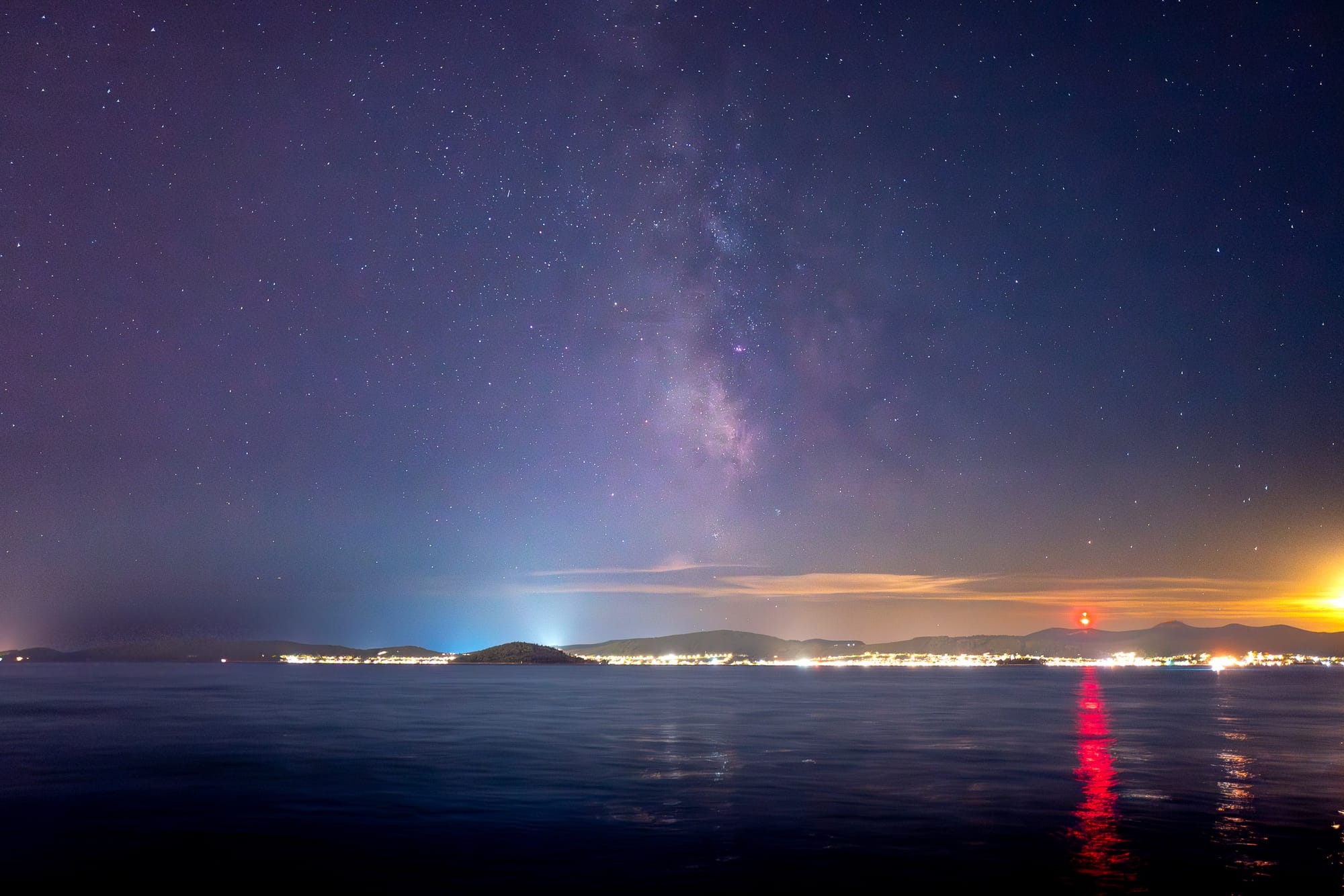 Above a series of islands and hills floats the Milky Way Galaxy