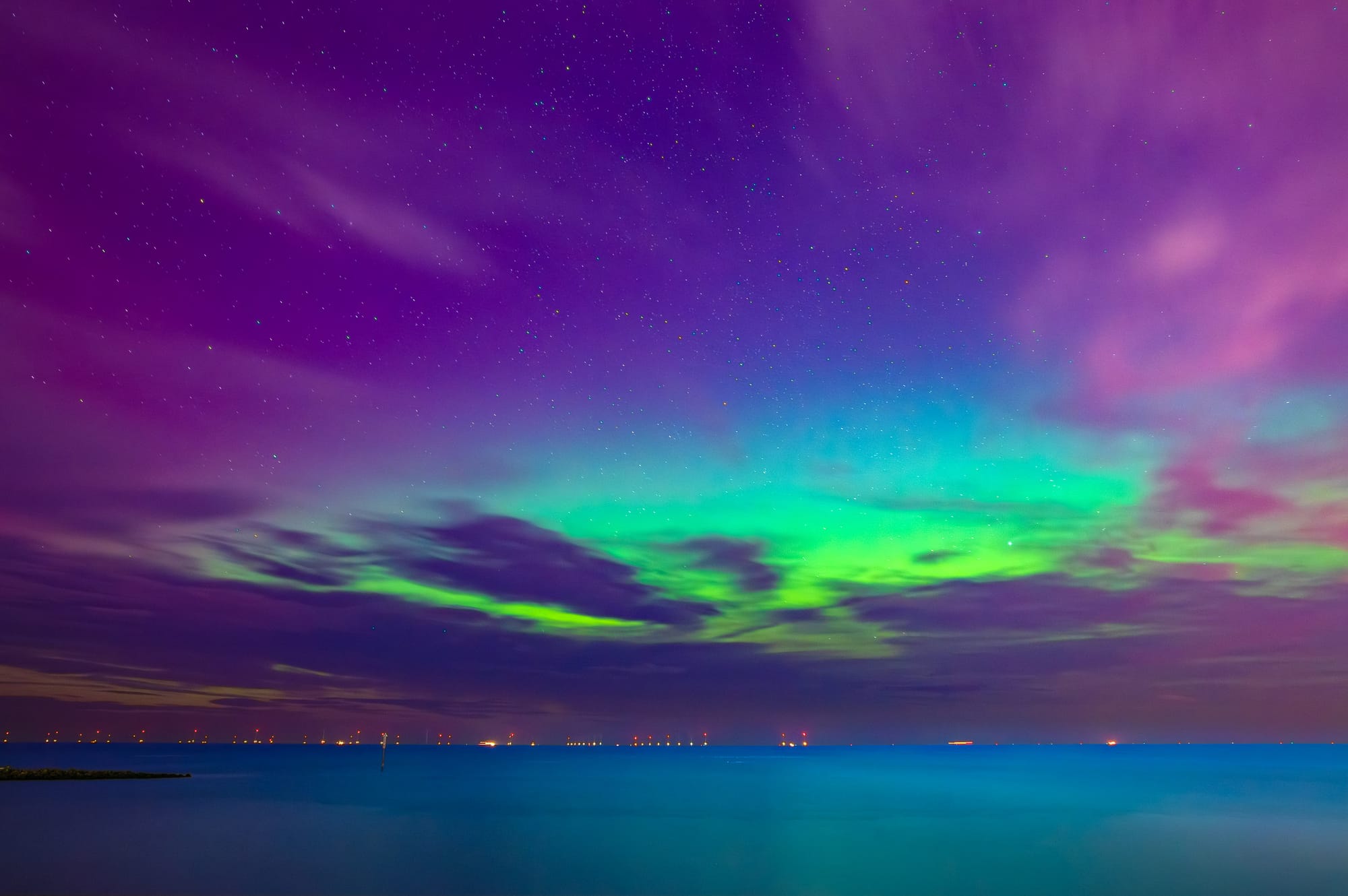 In the sky above Liverpool Bay there are pink clouds, stars and a green glow in the sky from the aurora.