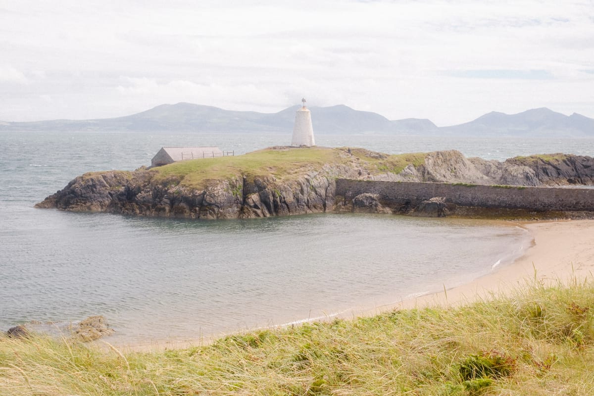 A serene coastal landscape featuring a small lighthouse perched on a rocky outcrop. 