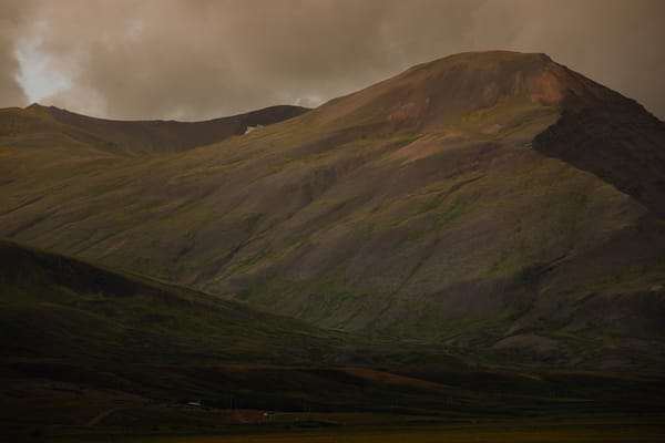 As the sun sets golden yellow light illuminates a mountain.