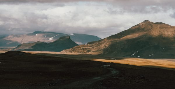 A thin road weaves its way towards mountain ranges in the distance.