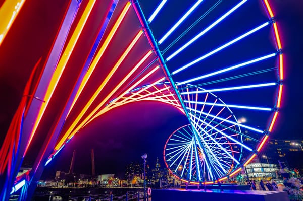 Night view of a light installation at the River of Light festival in Liverpool, with the city skyline in the background.