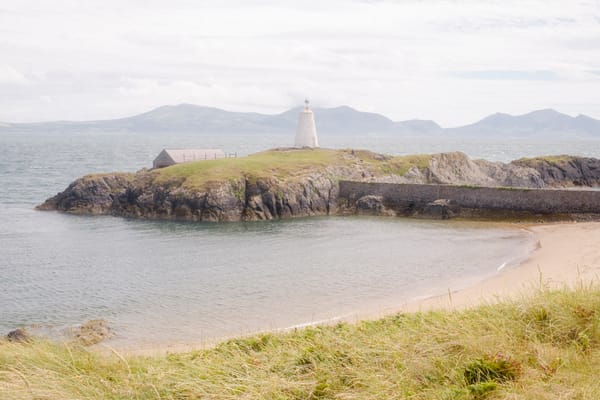 A serene coastal landscape featuring a small lighthouse perched on a rocky outcrop. 