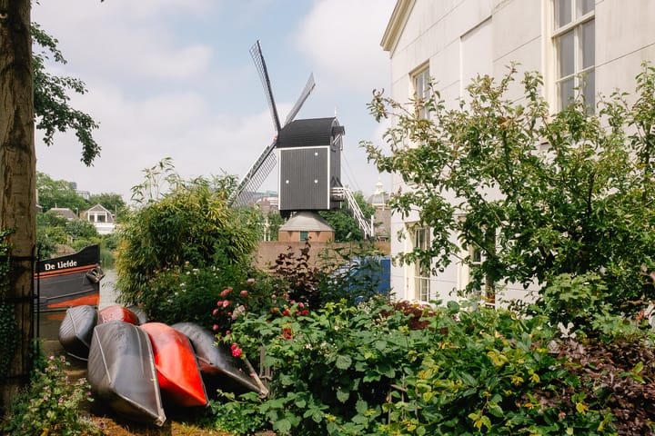 A windmill in Leiden, Netherlands. In the foreground there are kayaks and a boat.