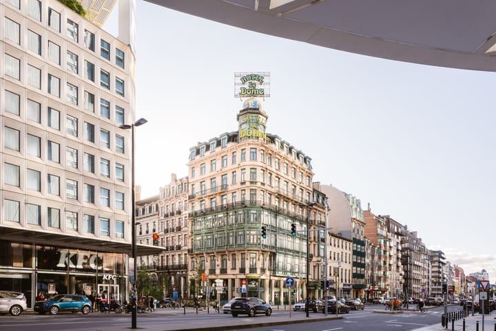 A busy street in Brussels. In the center is the Hotel le Dome.