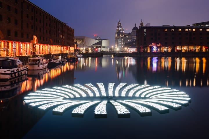 A circular led light installation floats in a dock creating the illusion of a portal.