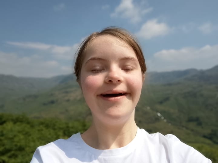 A person with Down's syndrome is contemplative on top of a hill.