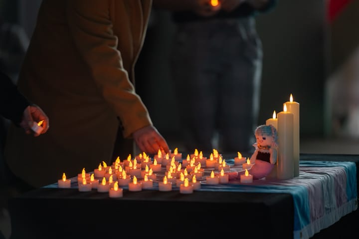 People place candles on a Trans flag to remember loved ones.