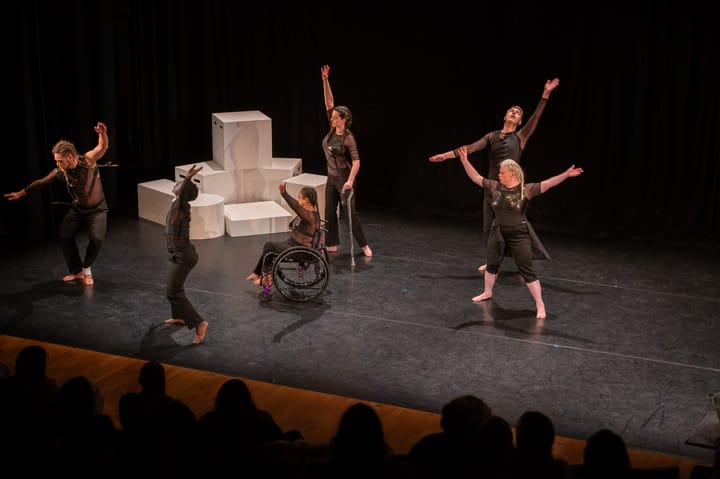 Diverse performers are on stage. One with a walking stick, one in a wheelchair, and one person with Downs Syndrome.