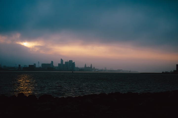 Sunset over the Mersey River, with the Liverpool skyline in the distance.