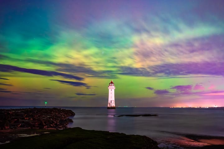 Green and purple aurora over New Brighton lighthouse as the tide rolls in.