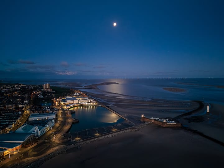 An aerial view of New Brighton Marine Lake in Liverpool Bay at dawn, with the moon visible in the sky.