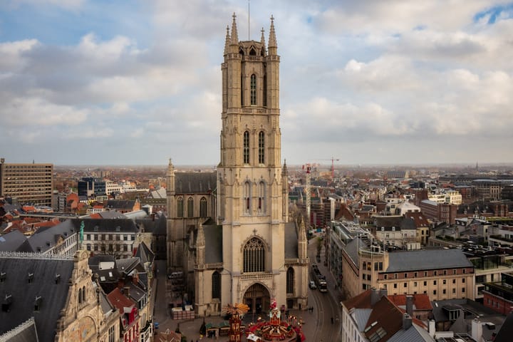 Aerial view of a tall, historic church tower rising above a cityscape.