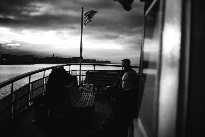 People sitting on the ferry as it travels to Liverpool on a stormy morning. Black and white.