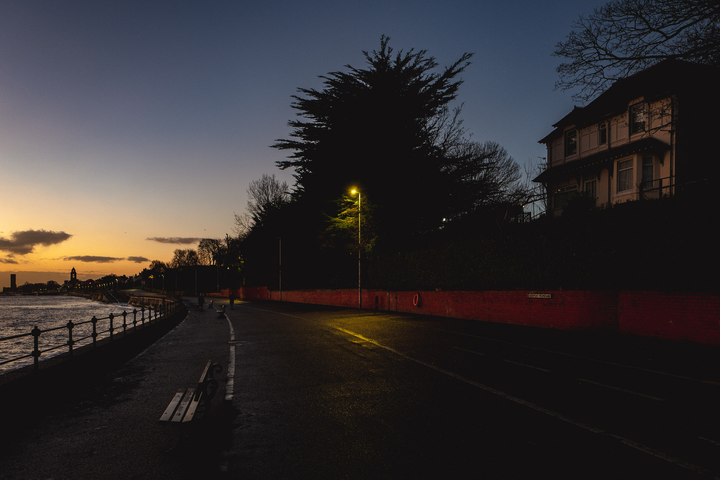 At dusk a single street light is turned on illuminating the promenade.