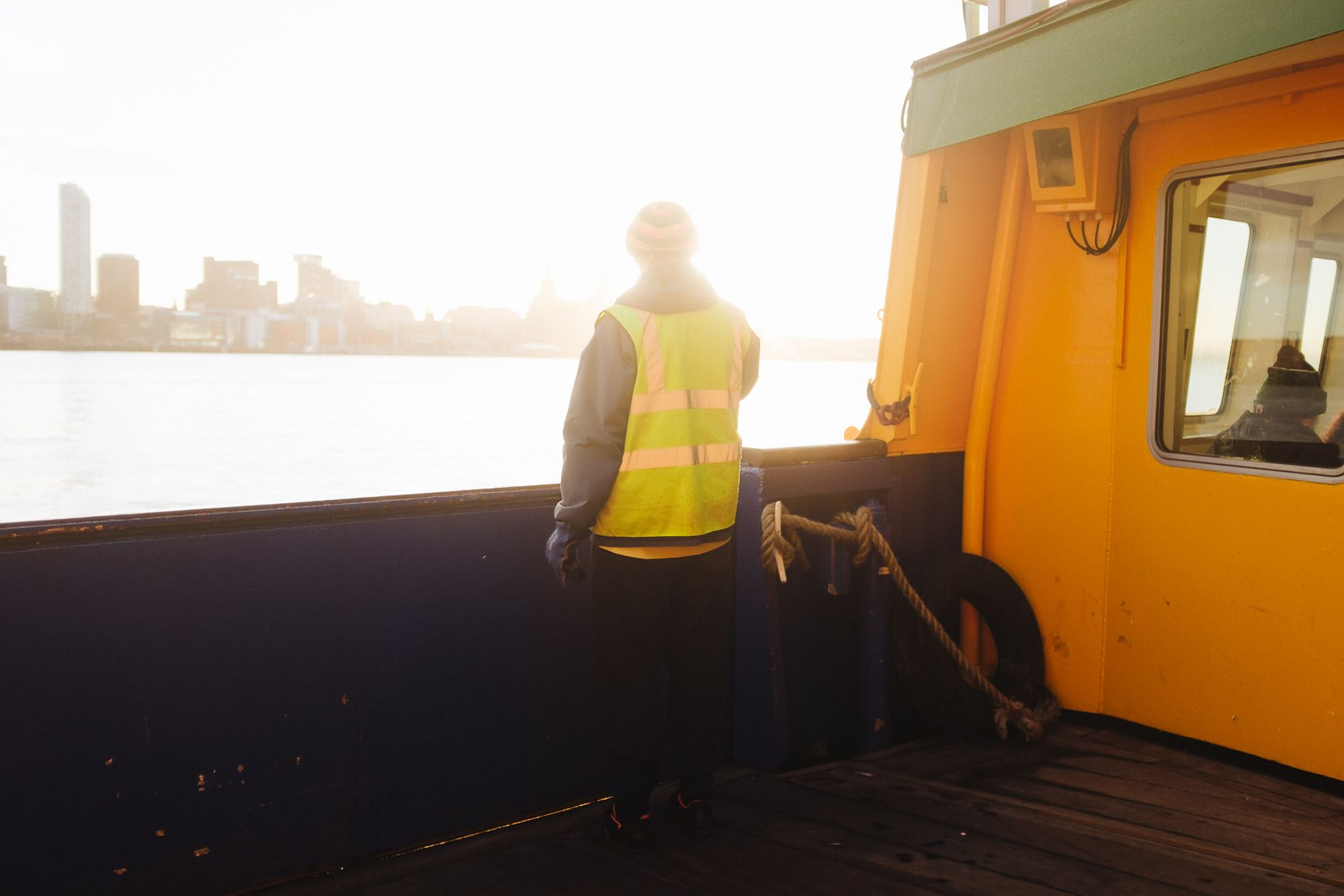 A person looks over the river as the ferry sails across the river.