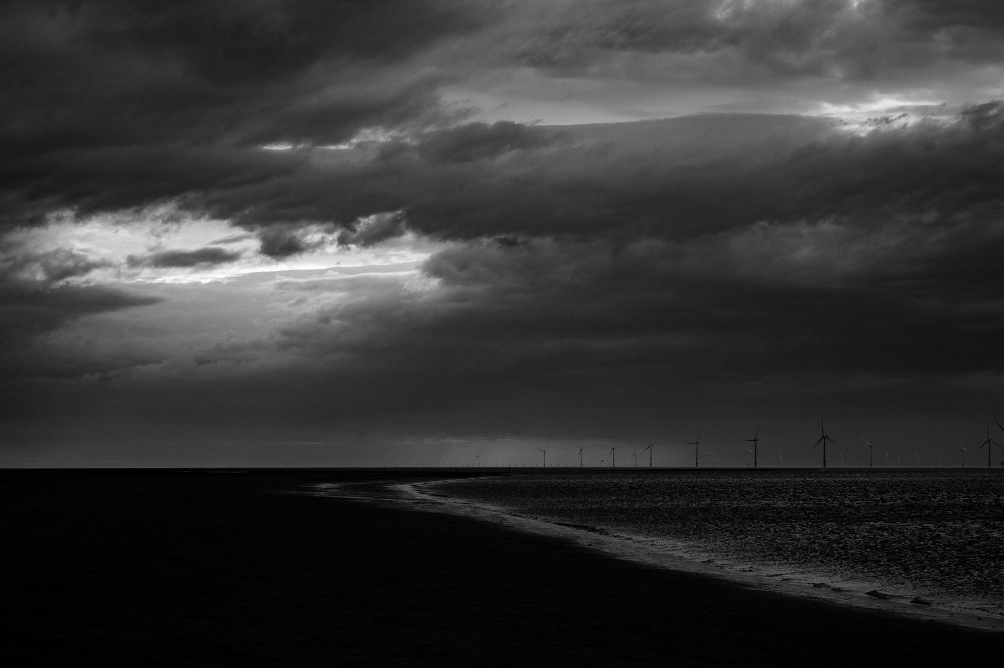 Wind turbines on the horizon on a dark overcast day.