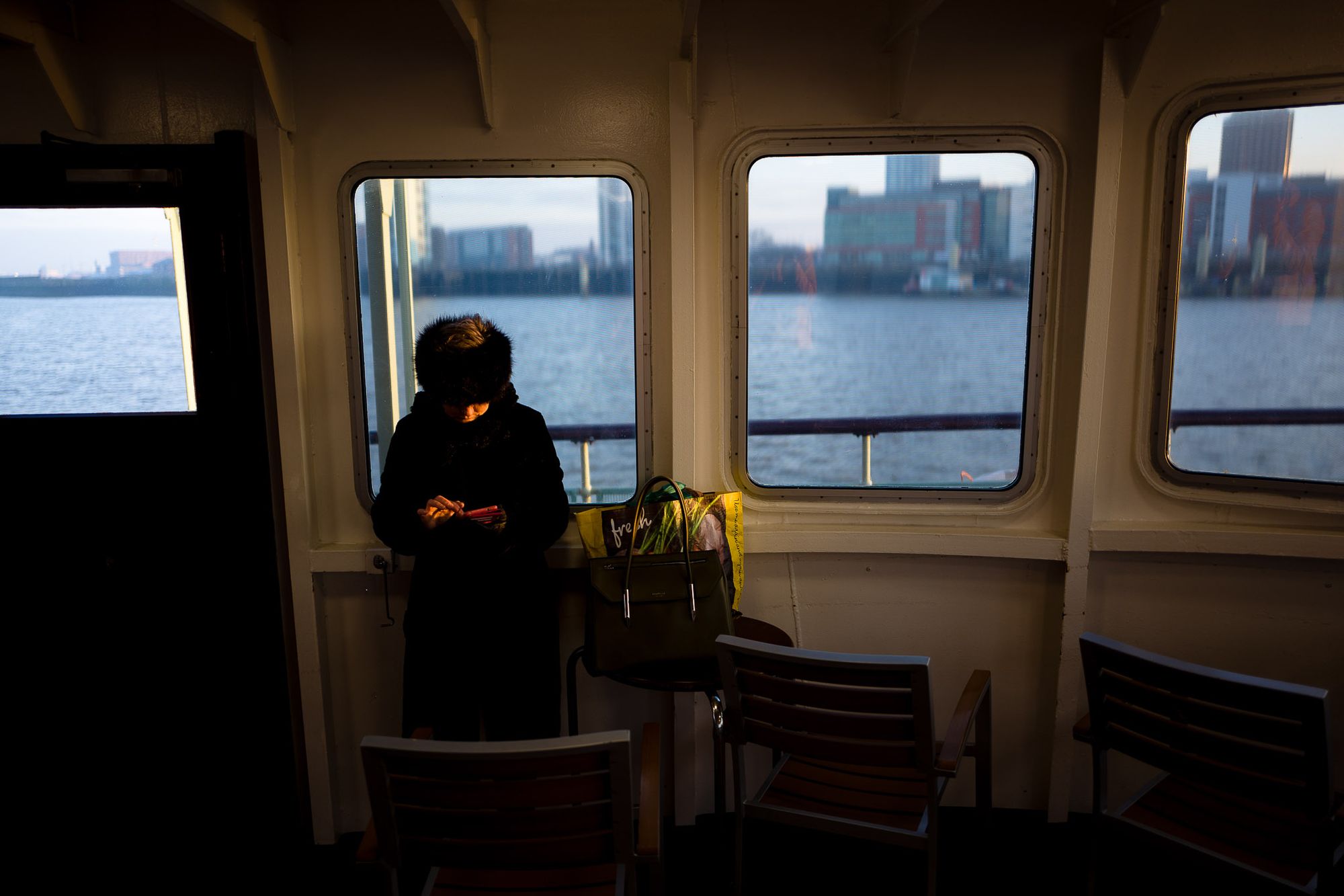 A woman uses her phone while the morning ferry sails into Liverpool