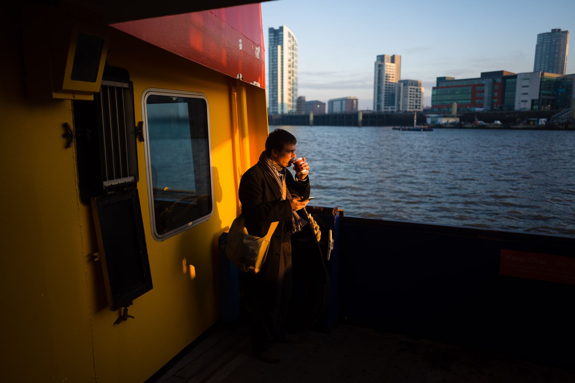 A man sips his morning coffee in the light of sunrise while sailing on the ferry to Liverpool