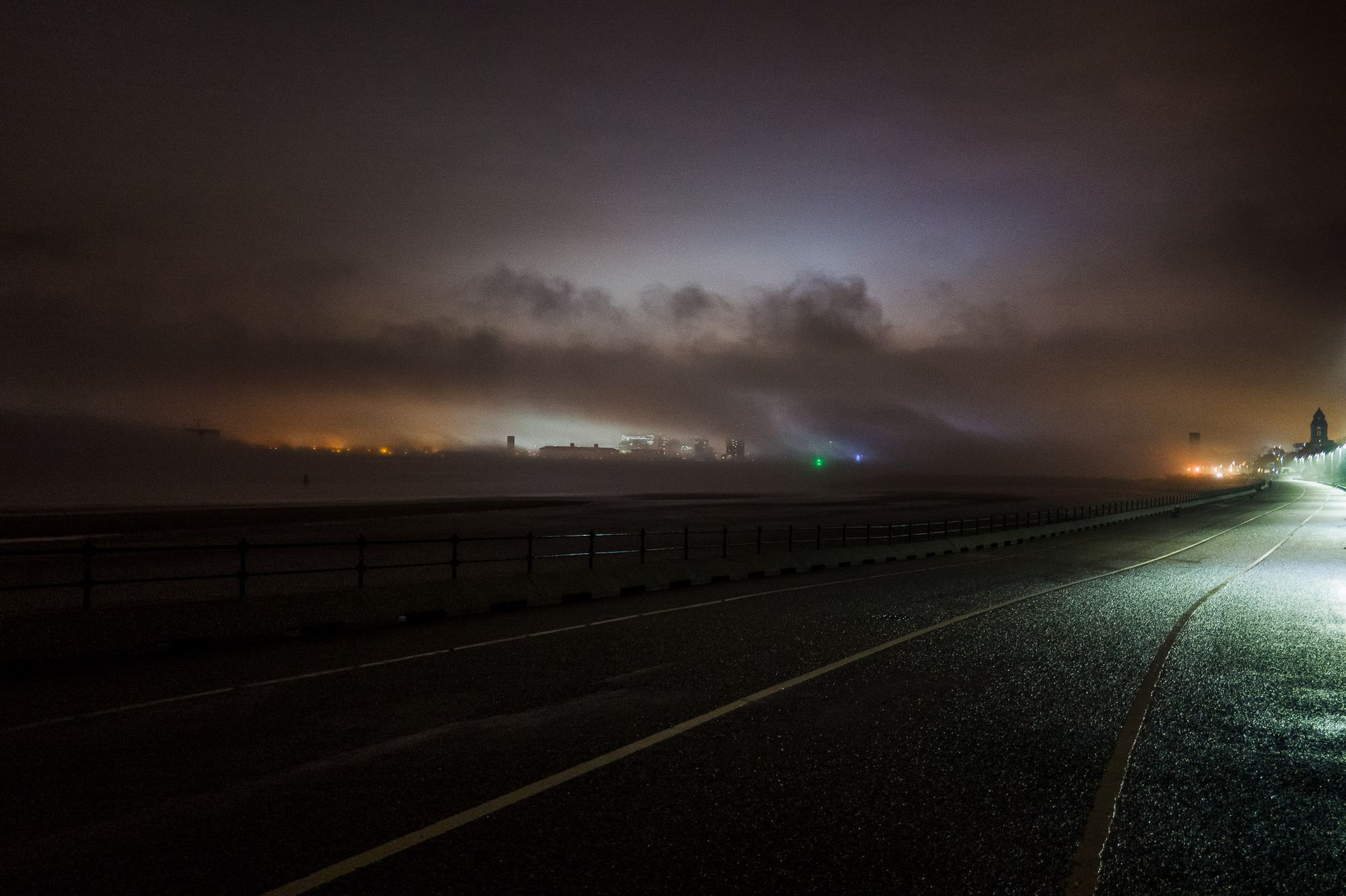 Fog flowing over the city of Liverpool at night.