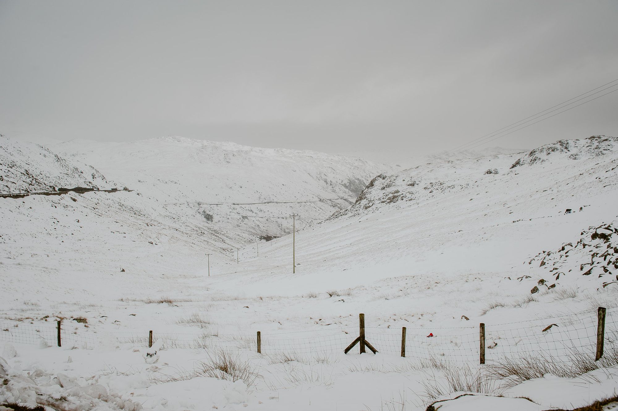 Snowy hills. There are telegraph poles leading down the hills.