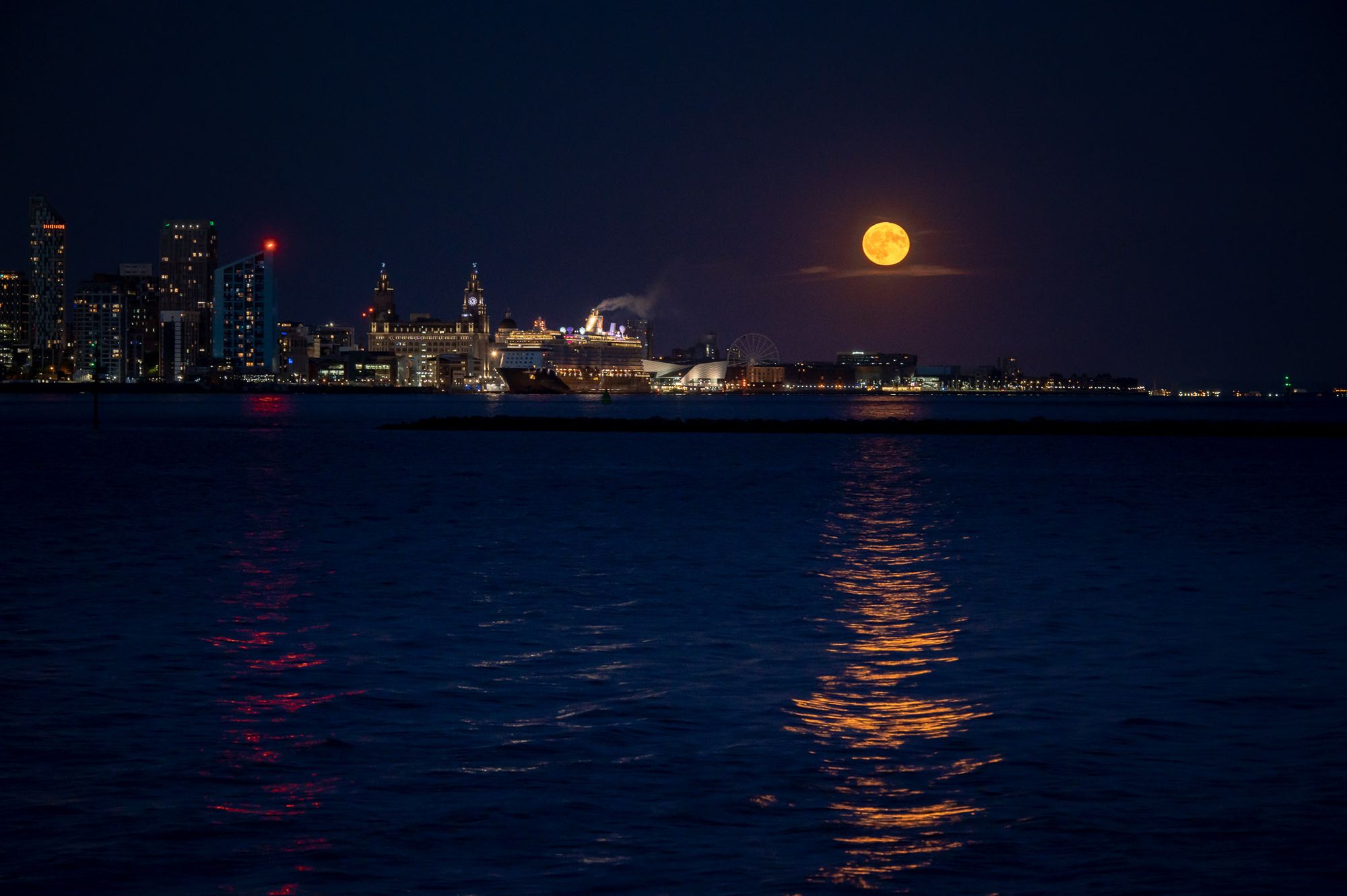 A Strawberry super moon rises to the right of the Liverpool skyline.