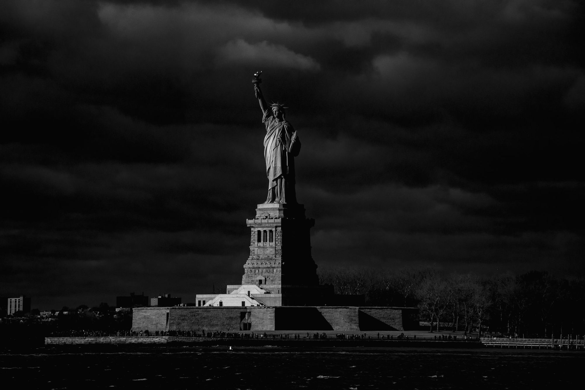 A black and white photo of the Statue of Liberty against a dark sky.