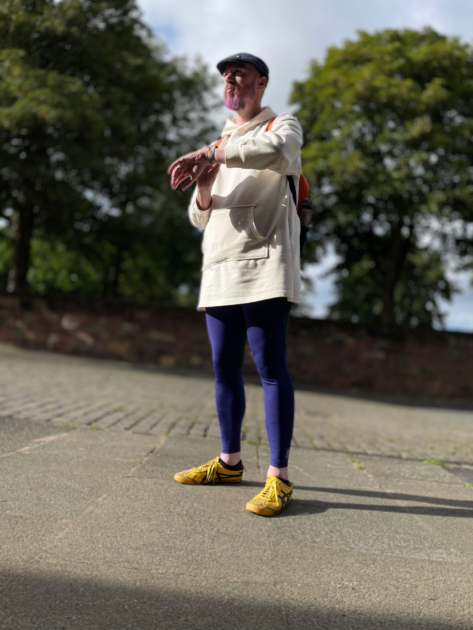 Non-binary person wearing a white hoodie dress and purple leggings.