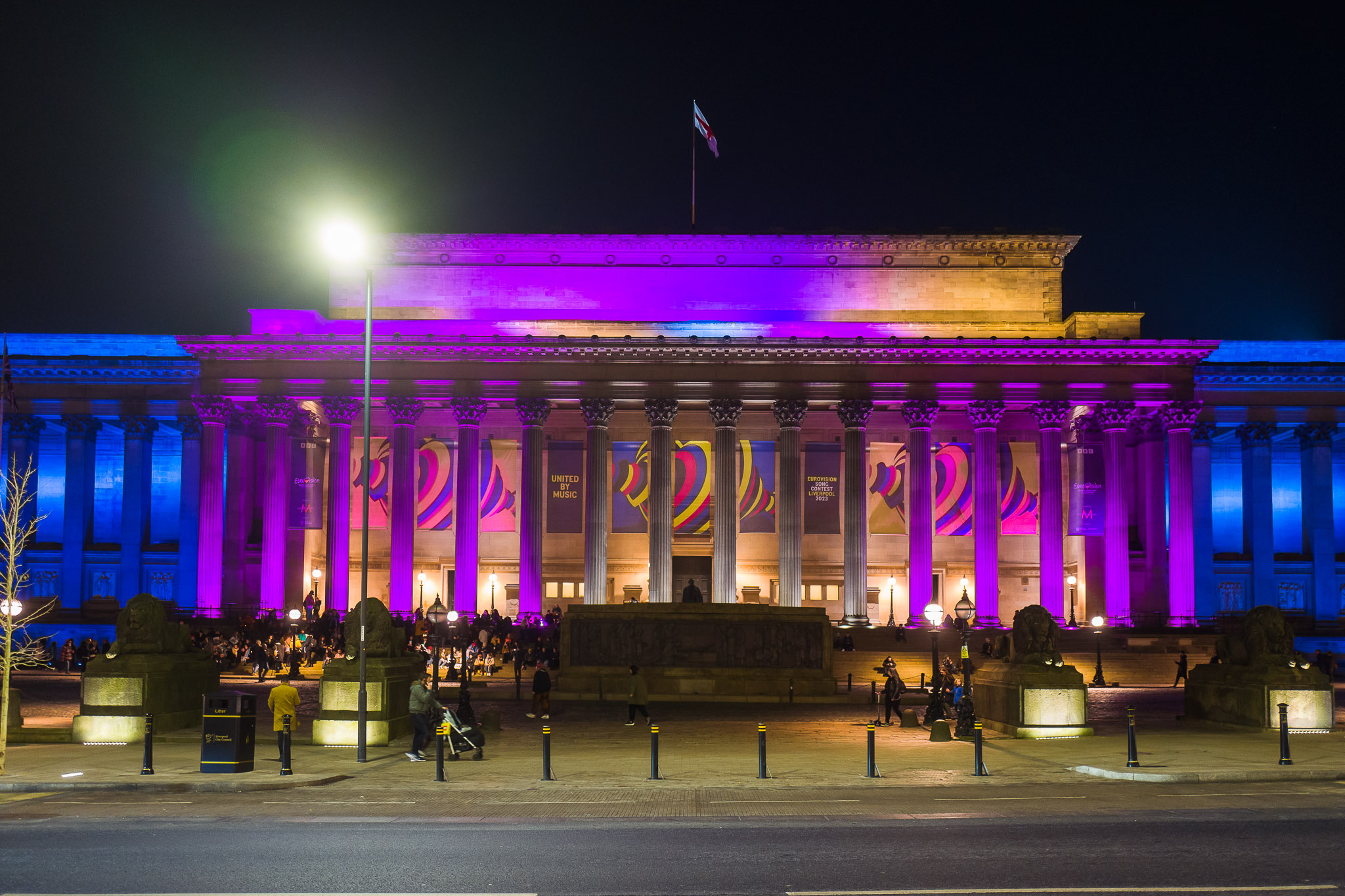 Wide view of St George's Hall lit up in the colours of the trans flag at night.