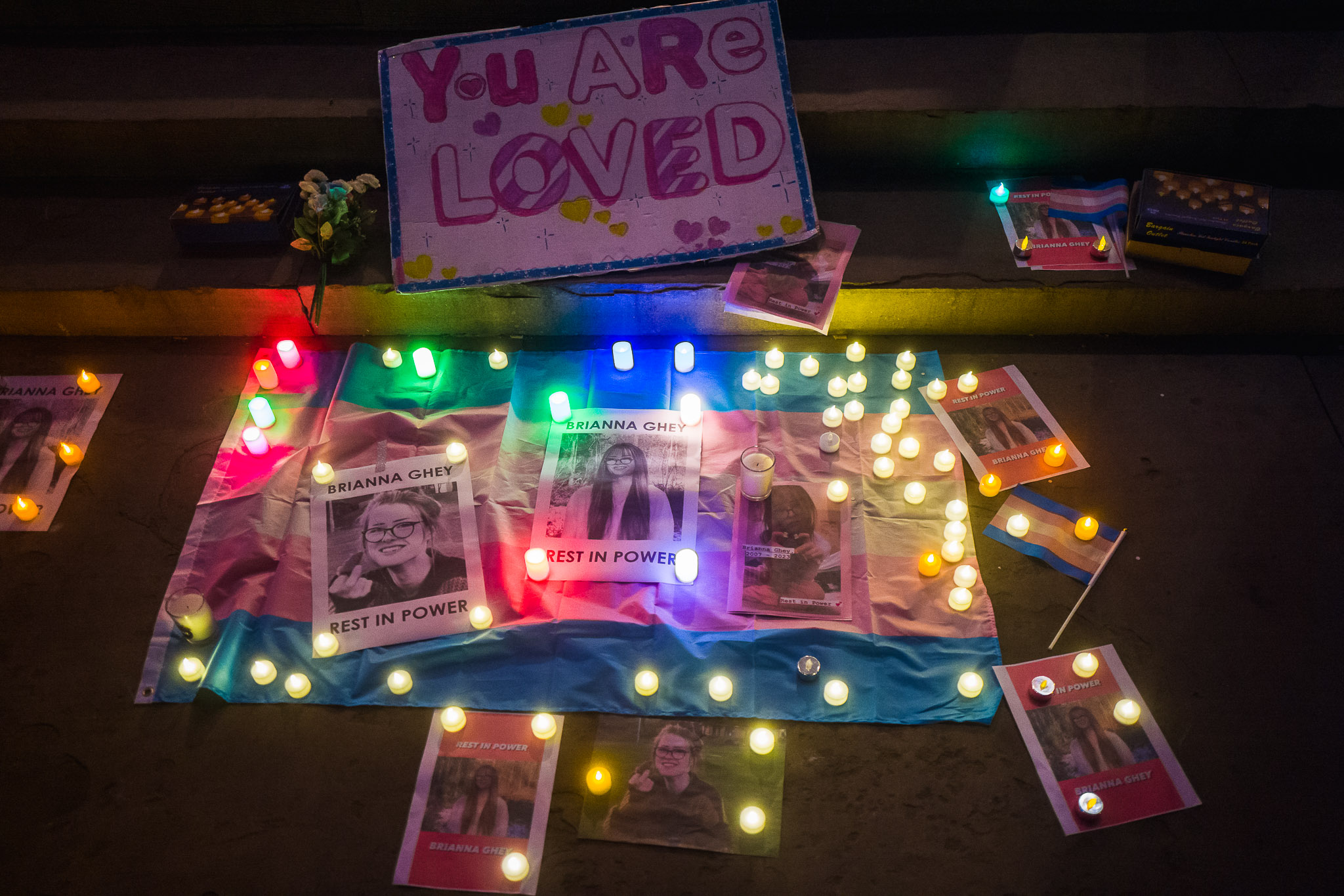 On the steps of St George's Hall lies a trans flag covered in messages of love and candles for Brianna Ghey.
