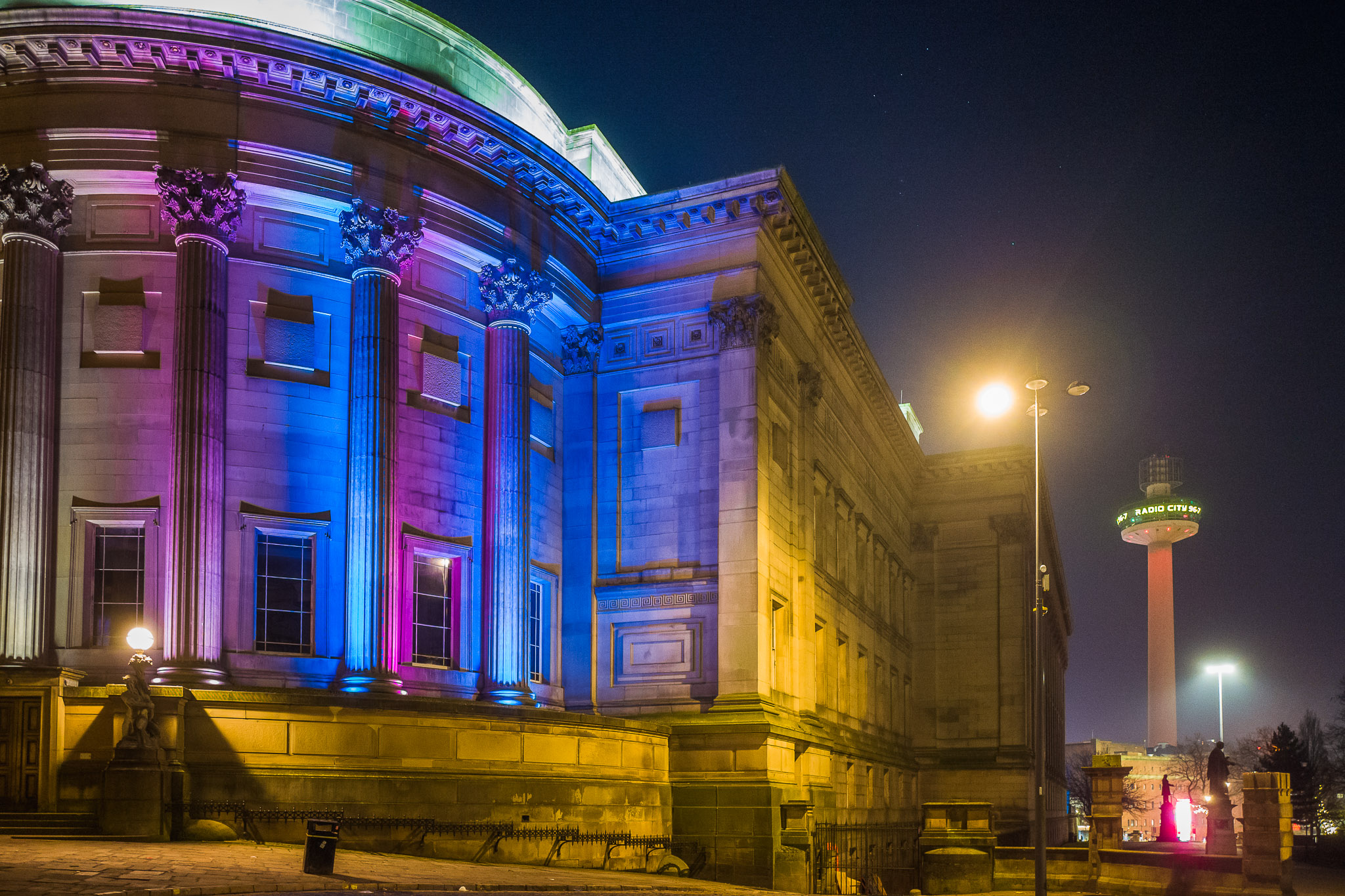 The corner of St George's Hall lit up in the trans flag colours. In the distance is St John's Beacon.